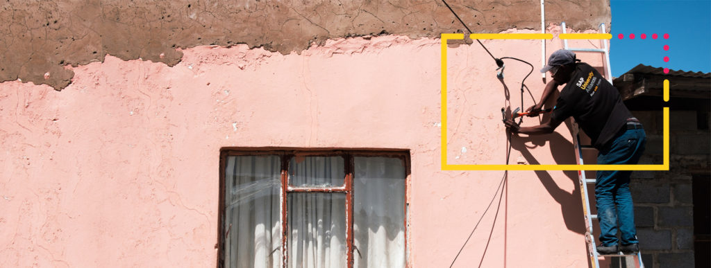 A man fixing wires to the wall of a house