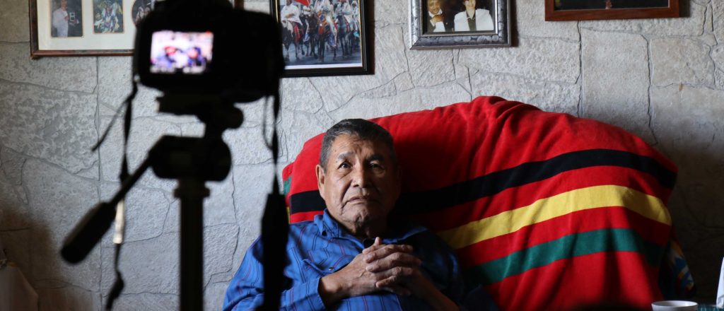 Piikani man at home being filmed