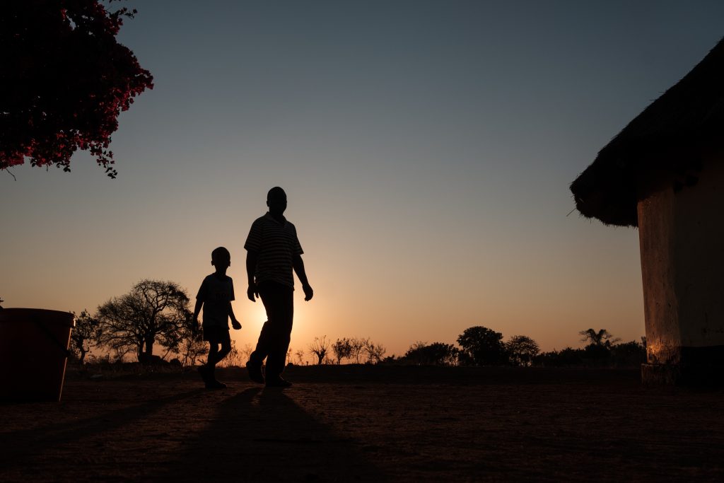 Man and boy silhouetted in front of a sunset