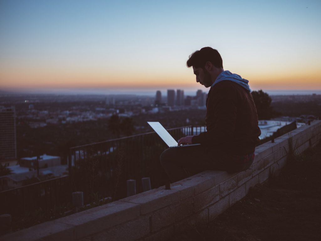 Man seated on bench with his laptop