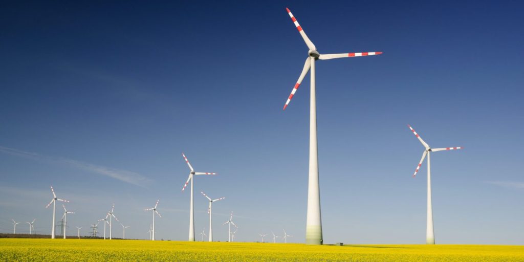 Wind turbines in a grass field against a blue sky