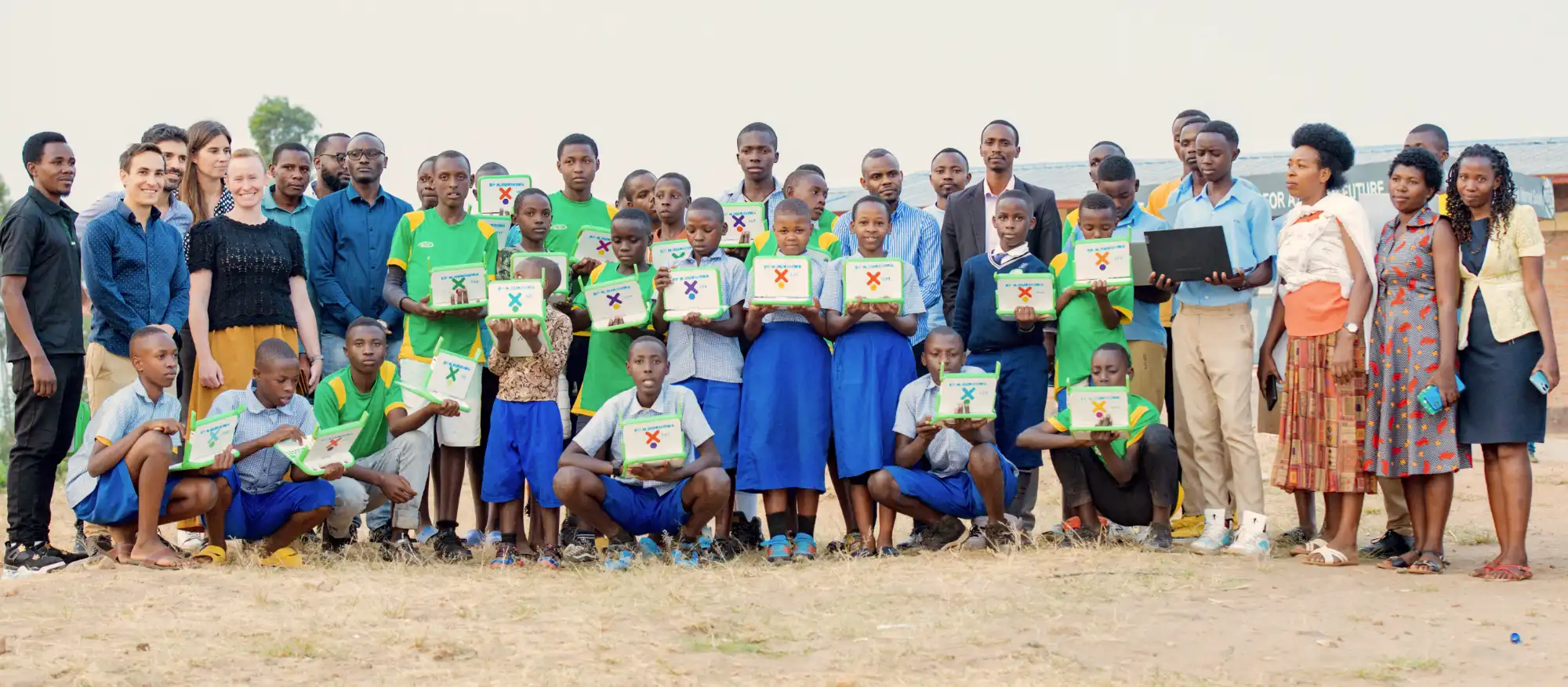 A group of students of a school in Rwanda and ISOC Foundation staff hold up laptops