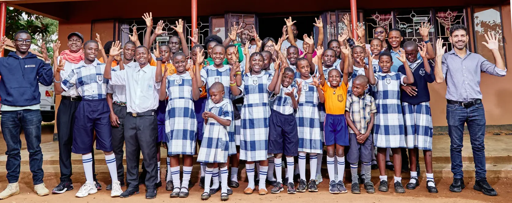 Pupils and ISOC Foundation staff wave their hands outside of a classroom