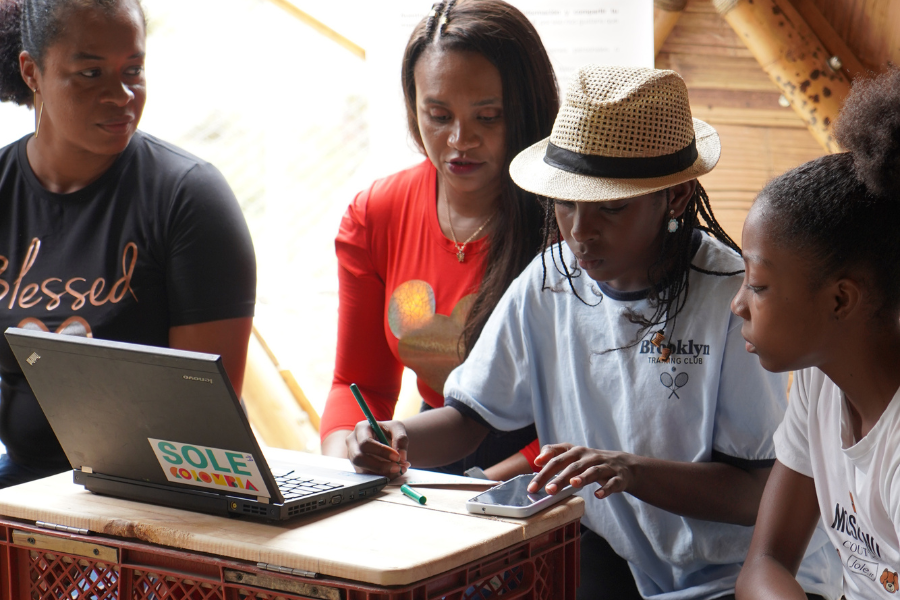 A group of young people works on a laptop.