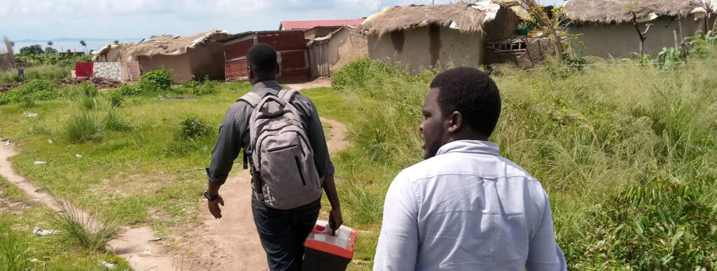 Two men walking in an african village with medical supplies