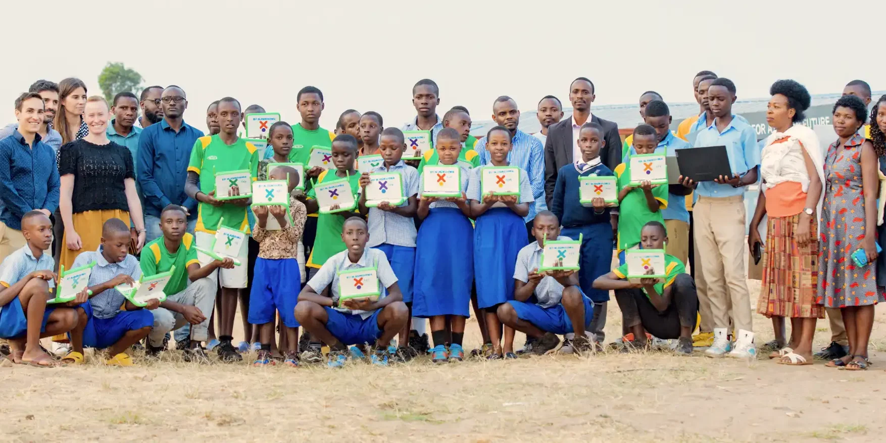 A group of students of a school in Rwanda and ISOC Foundation staff hold up laptops