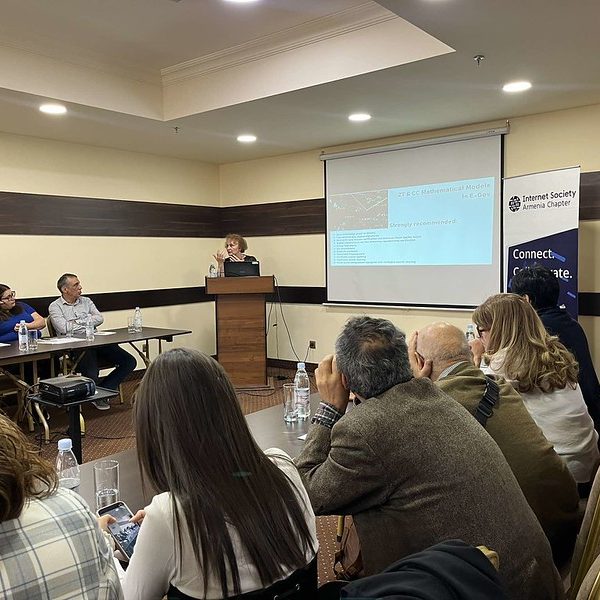 Participants listening to a female presenter in a conference room
