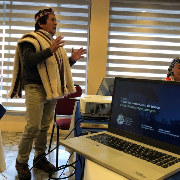 An indigenous man speaking in front of a laptop.