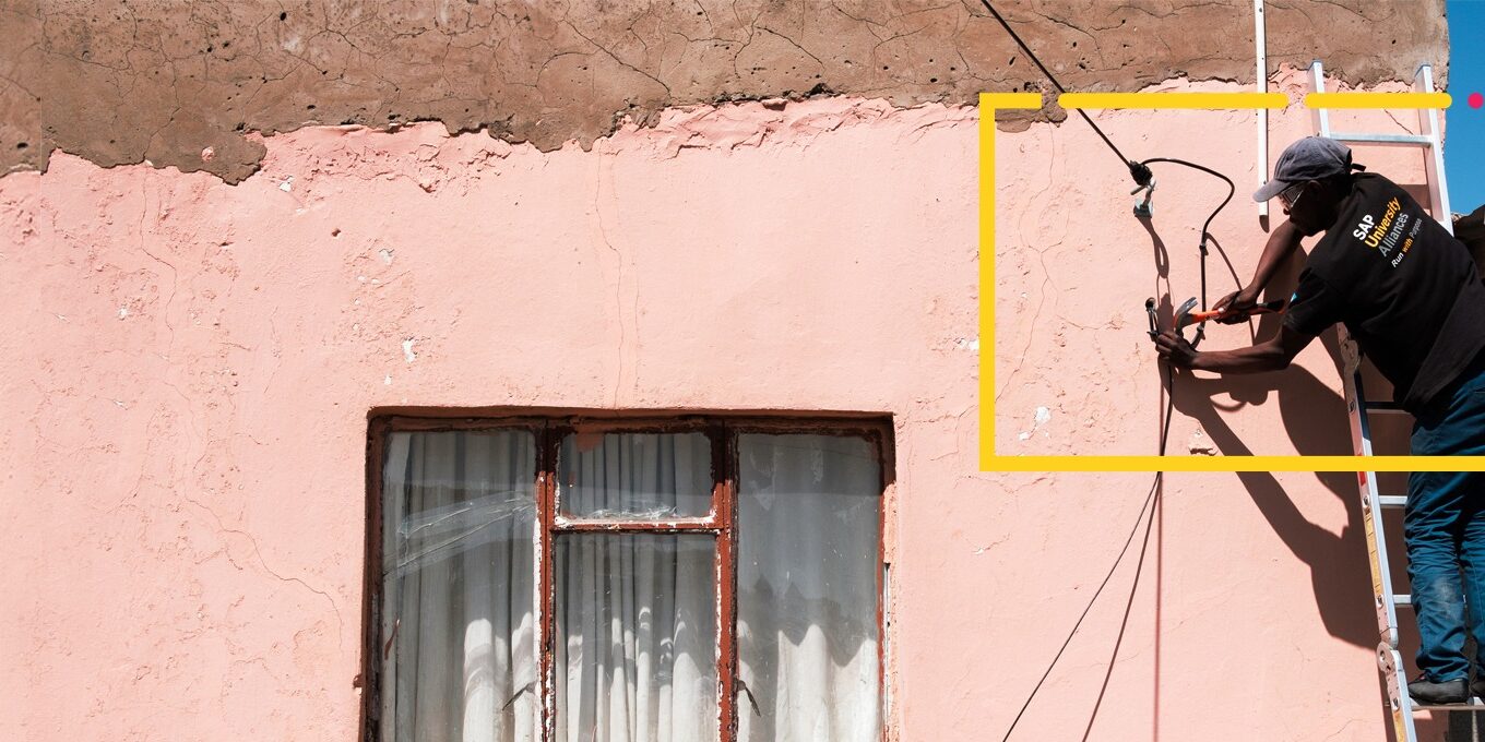 A man fixing wires to the wall of a house