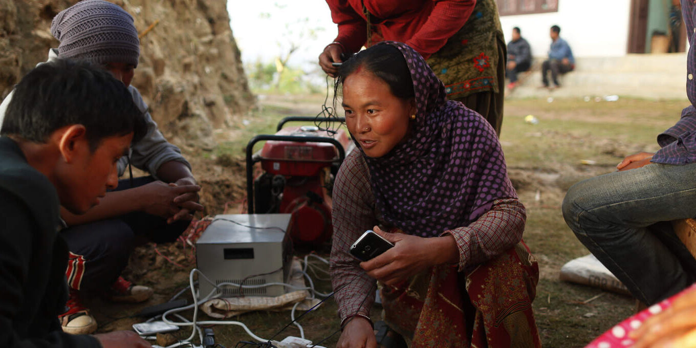 Young villagers giggle as they get the chance to charge their mobile phones from a generator in the destroyed village of Paslang near the epicenter of Saturday's massive earthquake in the Gorkha District of Nepal, Tuesday, April 28, 2015.  Military operations continue Tuesday to reach the isolated areas following the powerful earthquake that has devastated the nation and killed at least 4,400 people, according to district official Surya Mohan Adhikari. (AP Photo/Wally Santana)